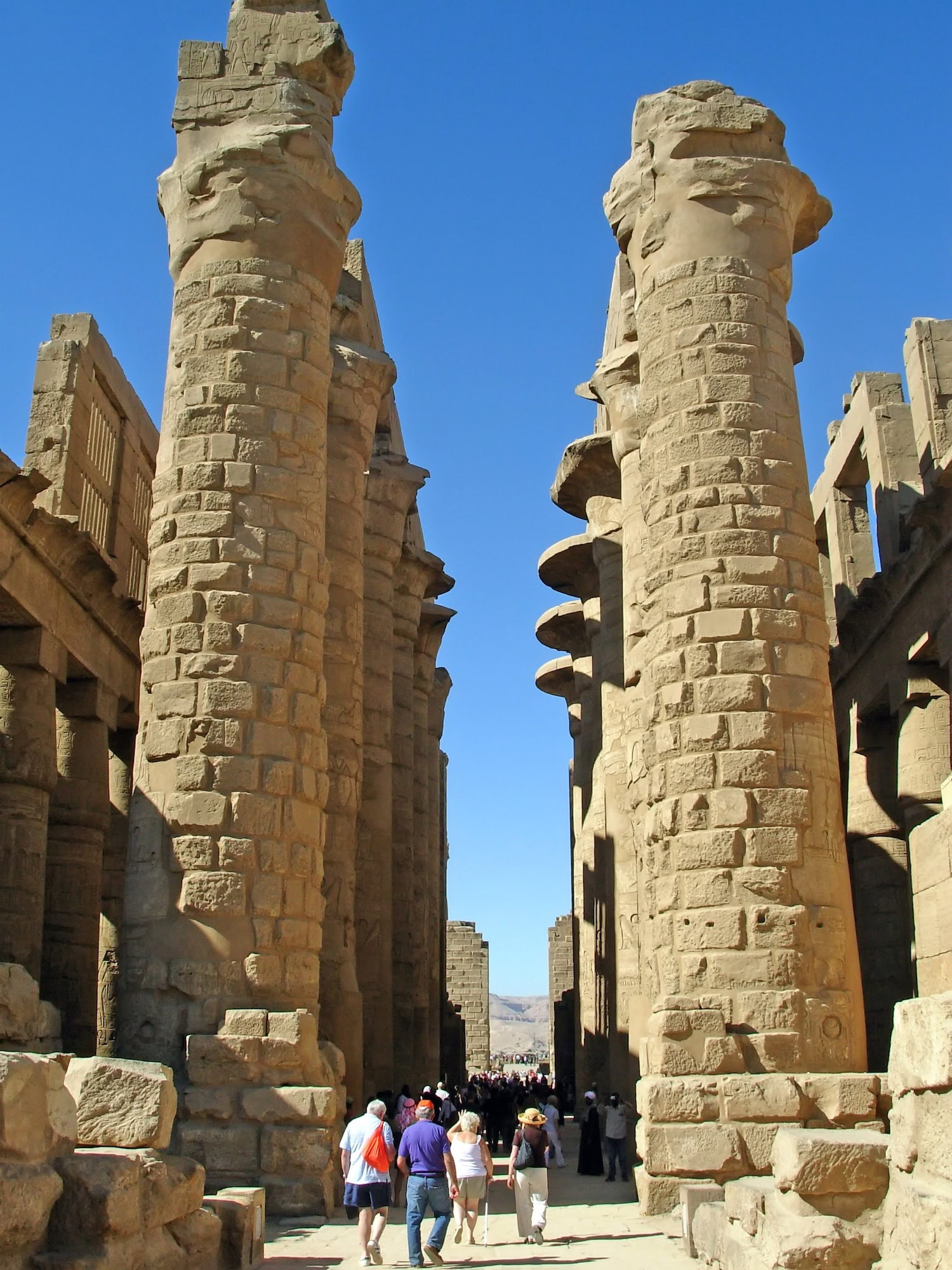 Tourists walking through ancient stone columns and ruins at Karnak Temple Complex