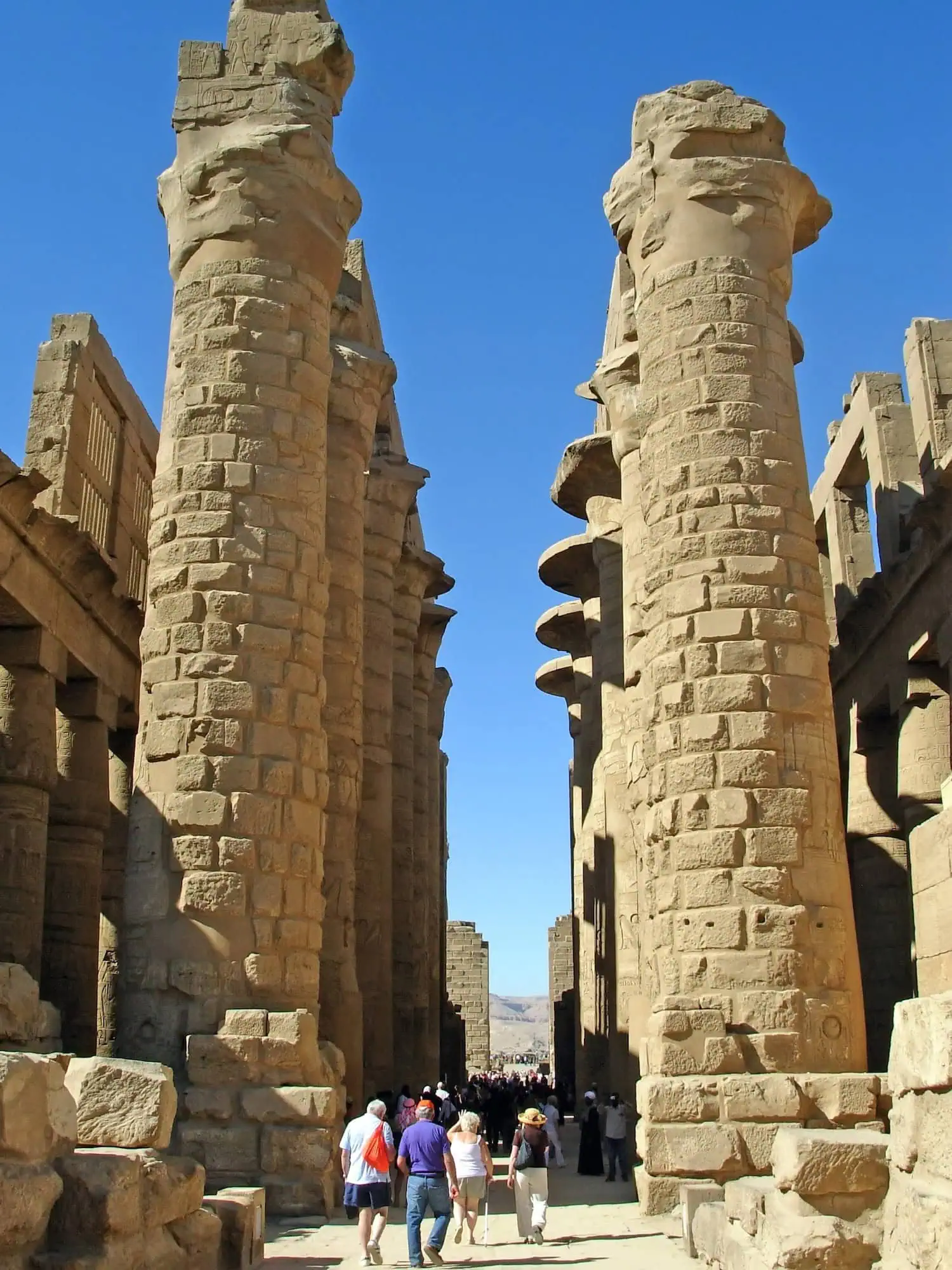 Tourists walking through ancient stone columns and ruins at Karnak Temple Complex