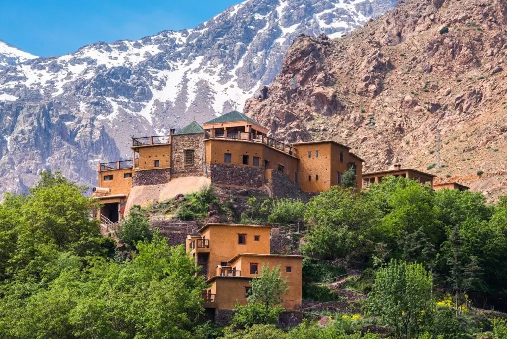 Kasbah du Toubkal built on a hillside with Atlas Mountain peaks in the background, Imlil