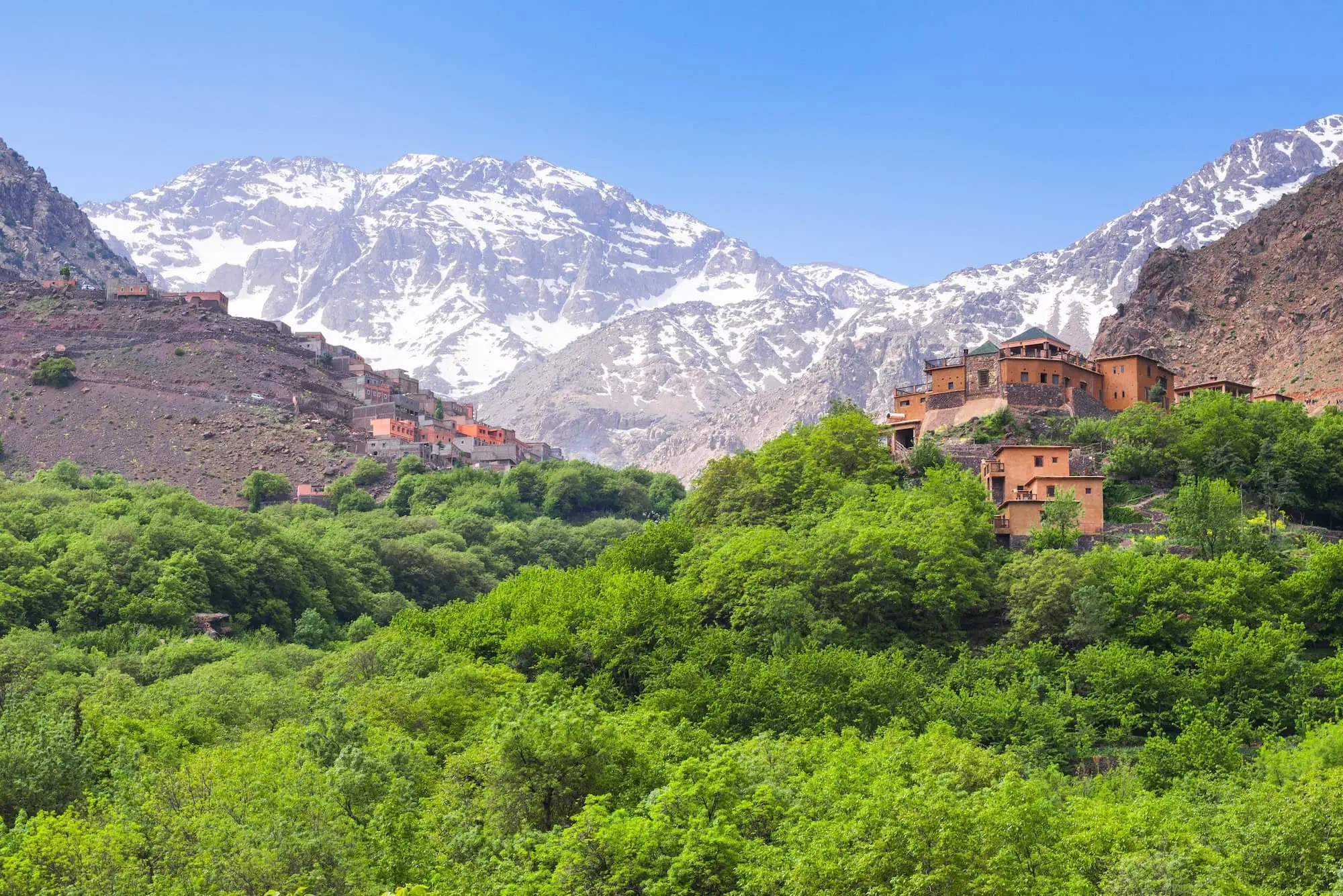 Traditional Berber buildings in Atlas Mountains near Imlil with snow-capped peaks in background