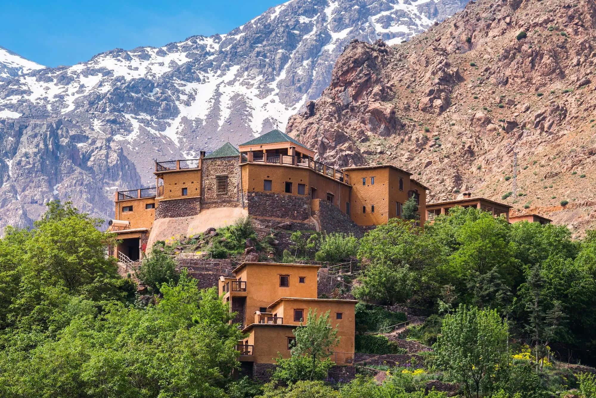 Traditional Kasbah du Toubkal building in Imlil with snow-capped Atlas mountains backdrop