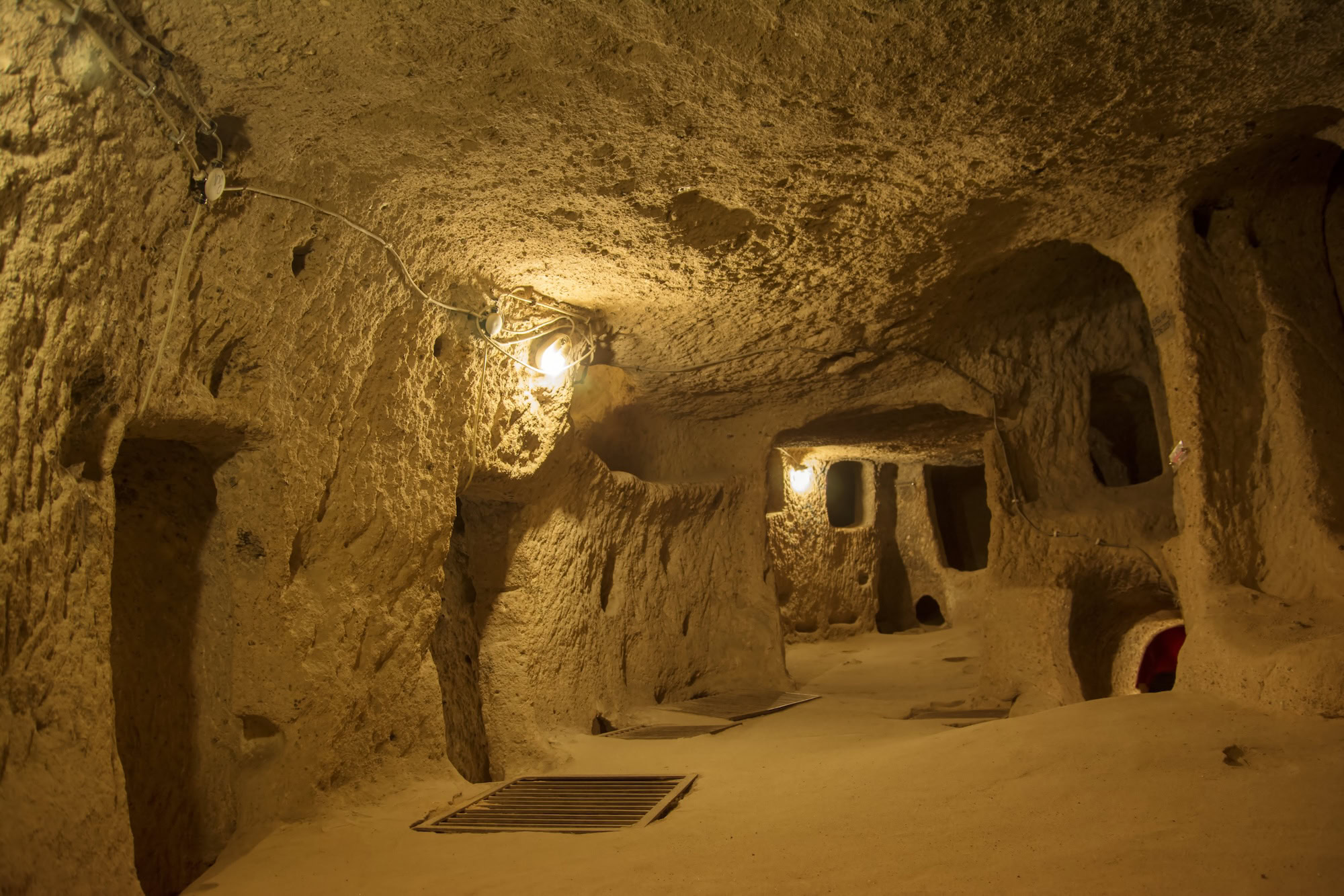 Underground city tunnel with carved stone archways and electric lighting in Cappadocia