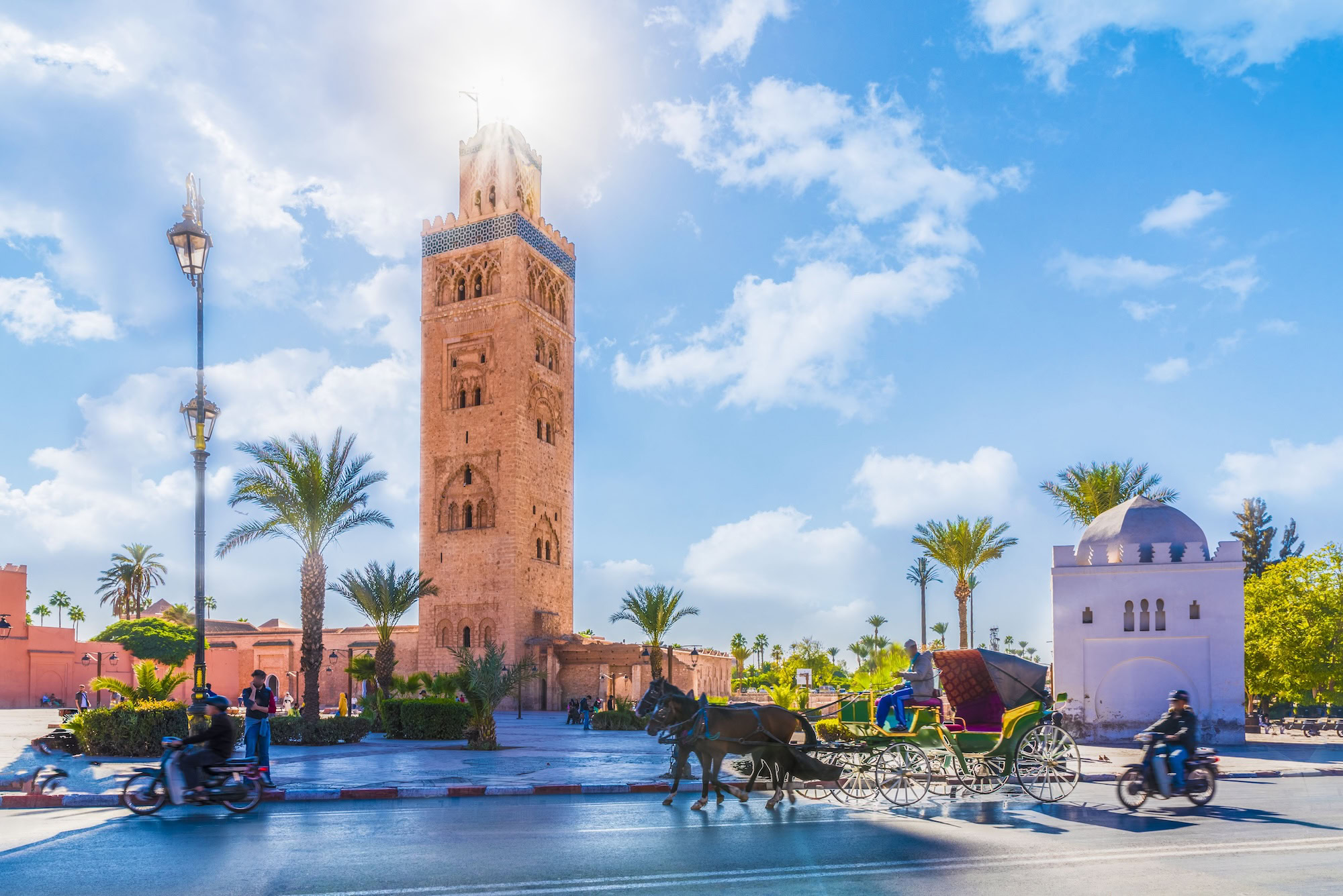 Koutoubia Mosque minaret with horse carriage and palm trees in Marrakech