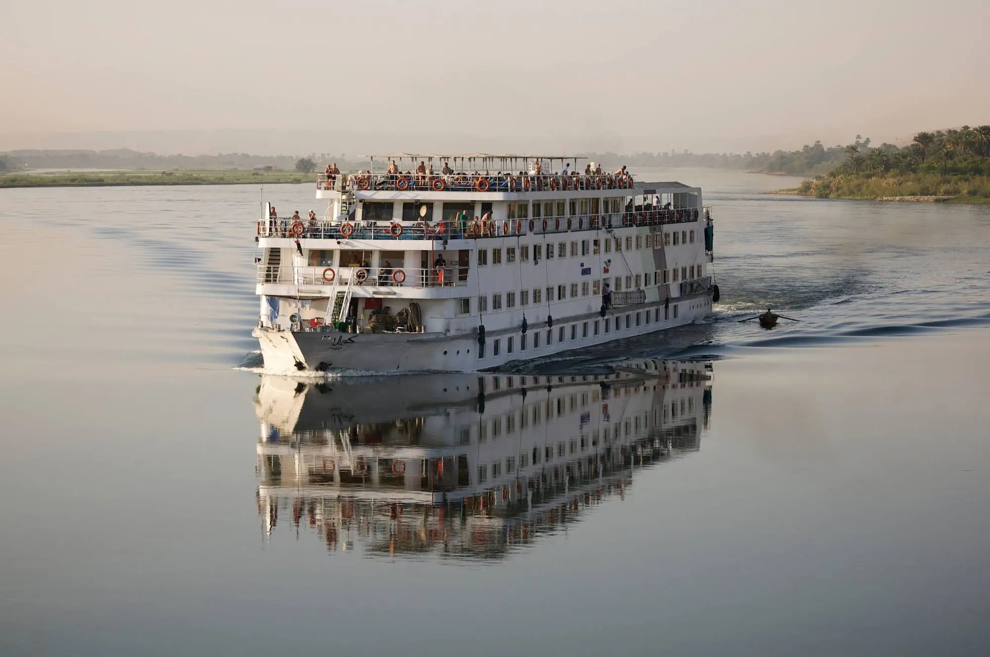 Nile River cruise ship with passengers on deck sailing through Egypt