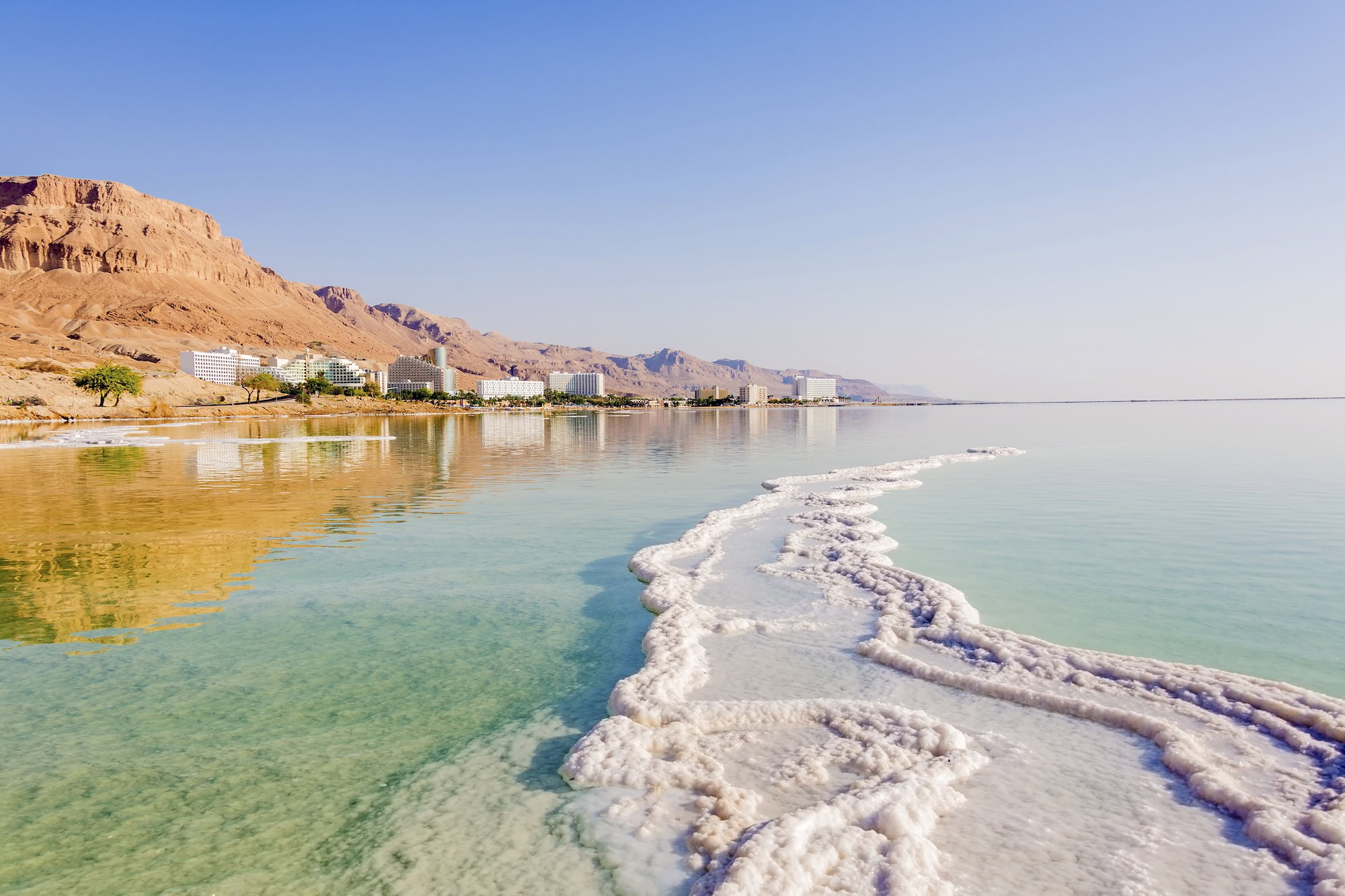 Luxury hotels and spa facilities along the Dead Sea shoreline with salt formations