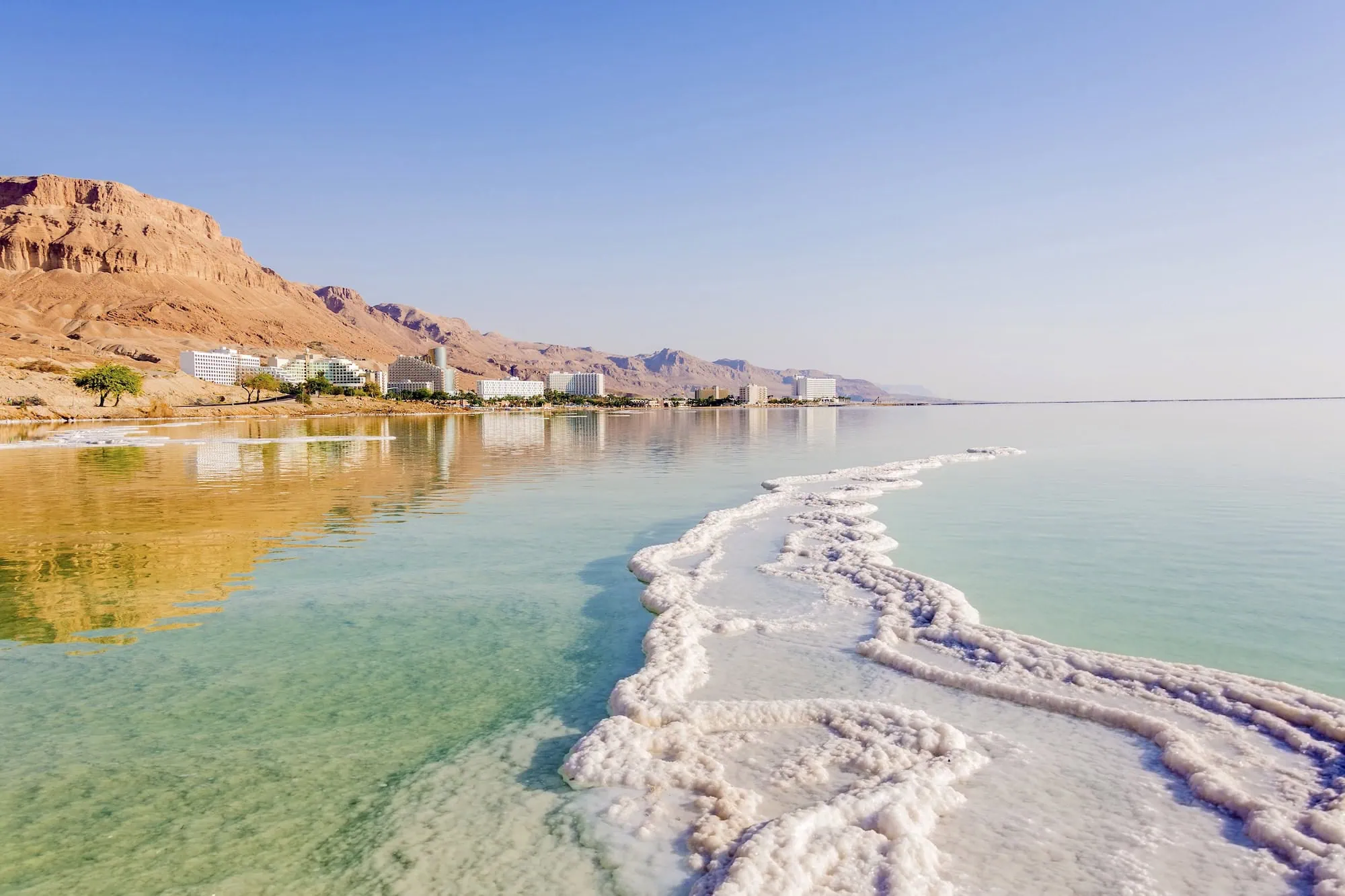 Luxury hotels and spa facilities along the Dead Sea shoreline with salt formations