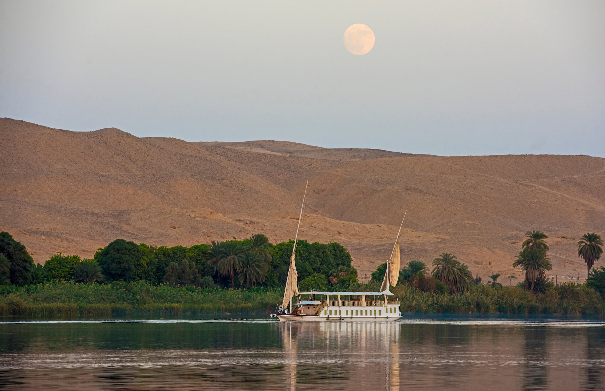 Large luxury traditional Egyptian dahabeya river boat sailing on the Nile with reflection and moon in sky 1 1