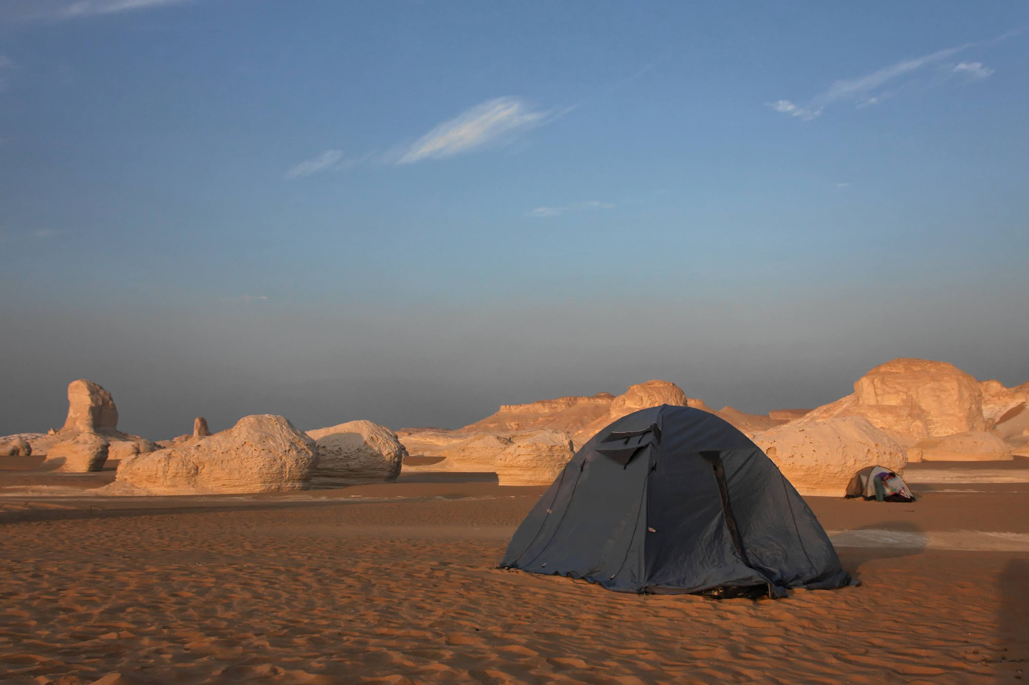 Camping tent set up among white limestone formations in Egypt's White Desert