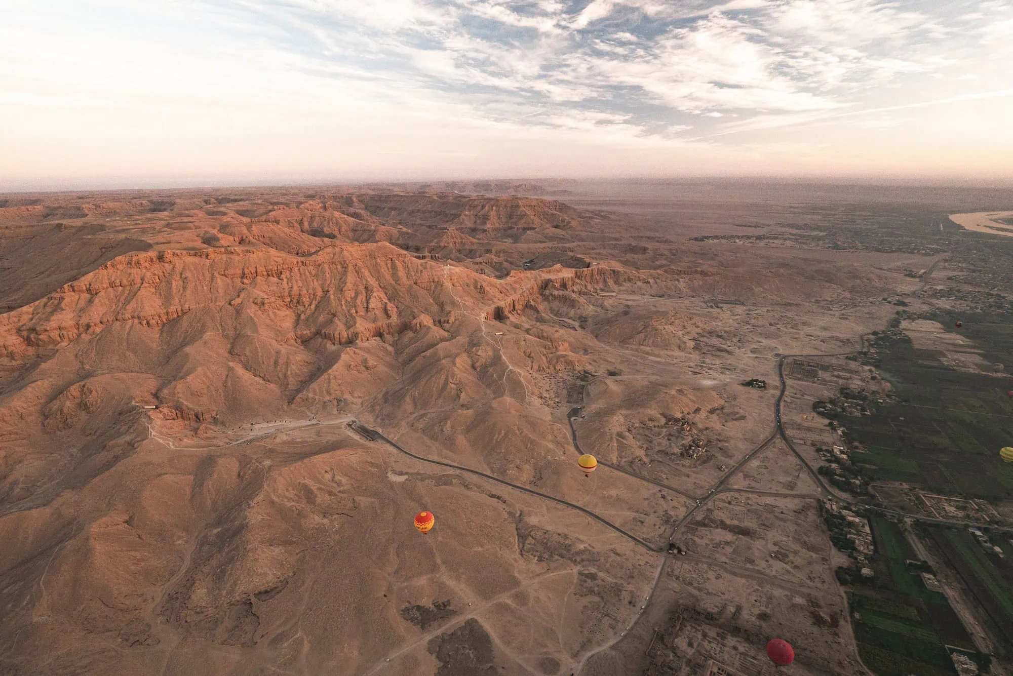 Hot air balloons floating over Valley of the Kings desert landscape
