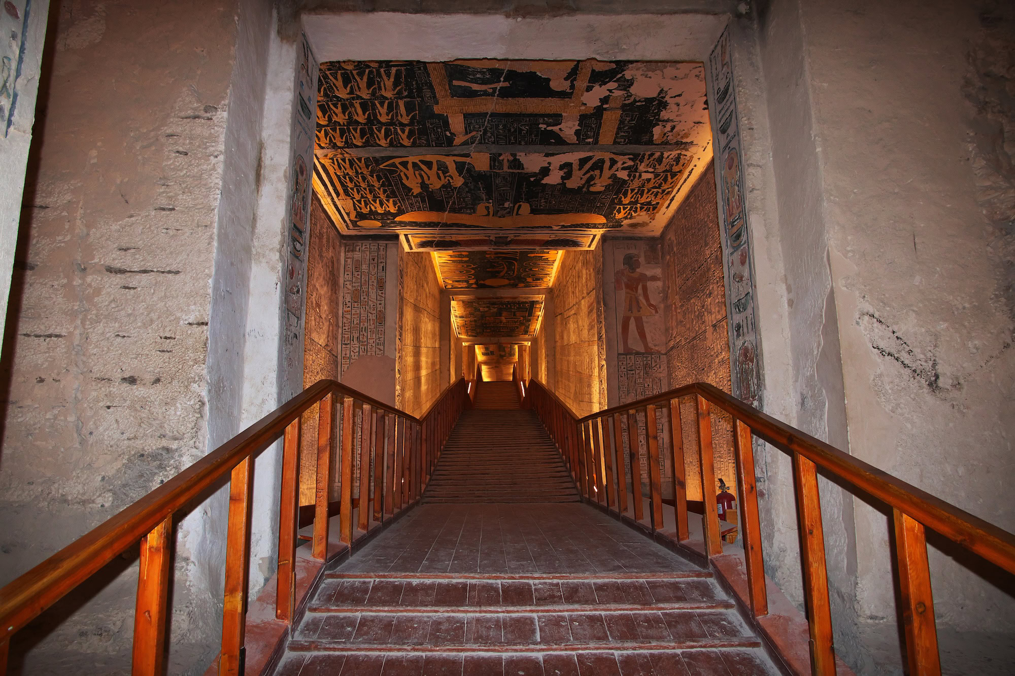 Illuminated Egyptian tomb interior with hieroglyphics and decorated walls