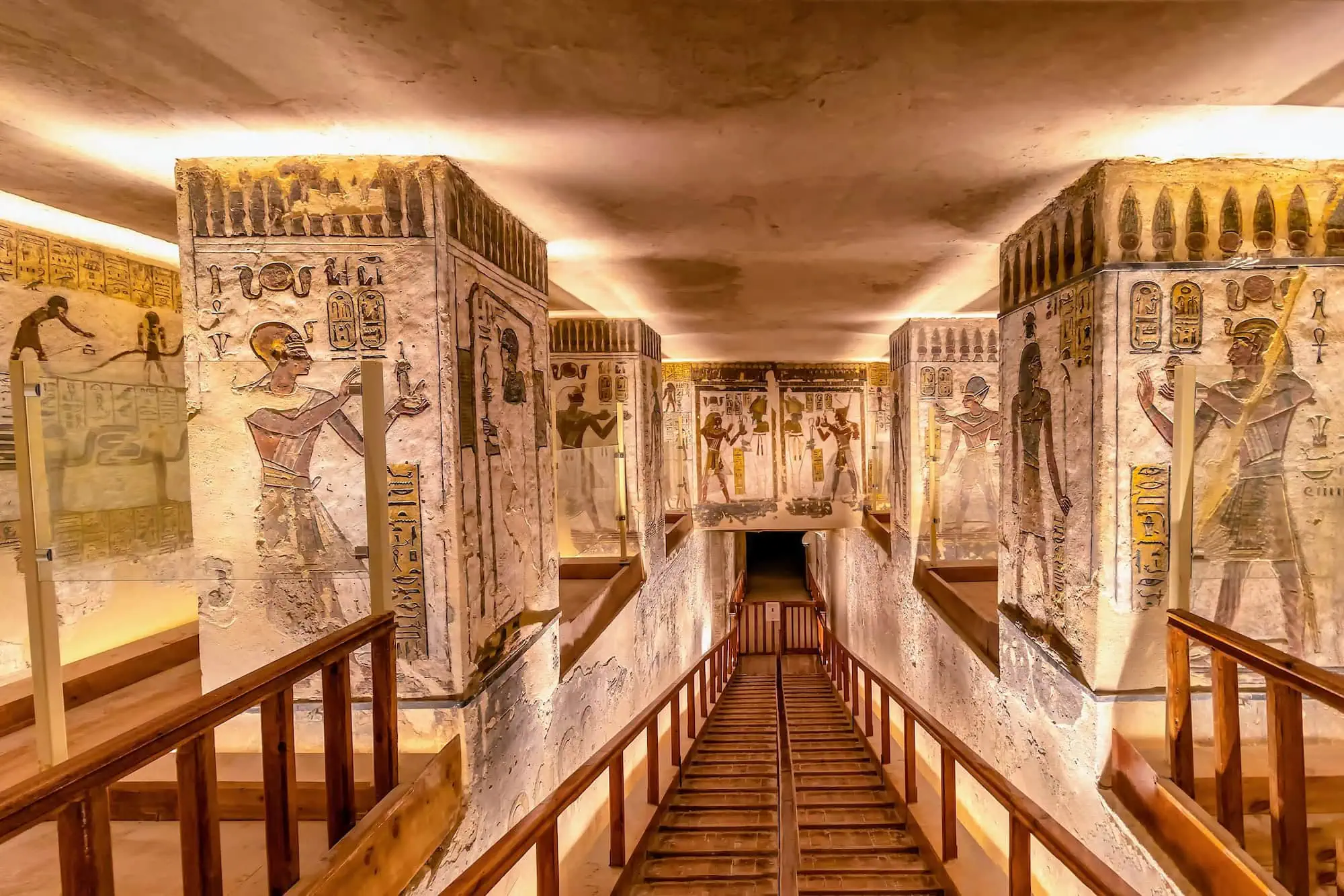 Interior of ancient Egyptian tomb showing elaborate wall paintings with hieroglyphics and colorful murals depicting deities