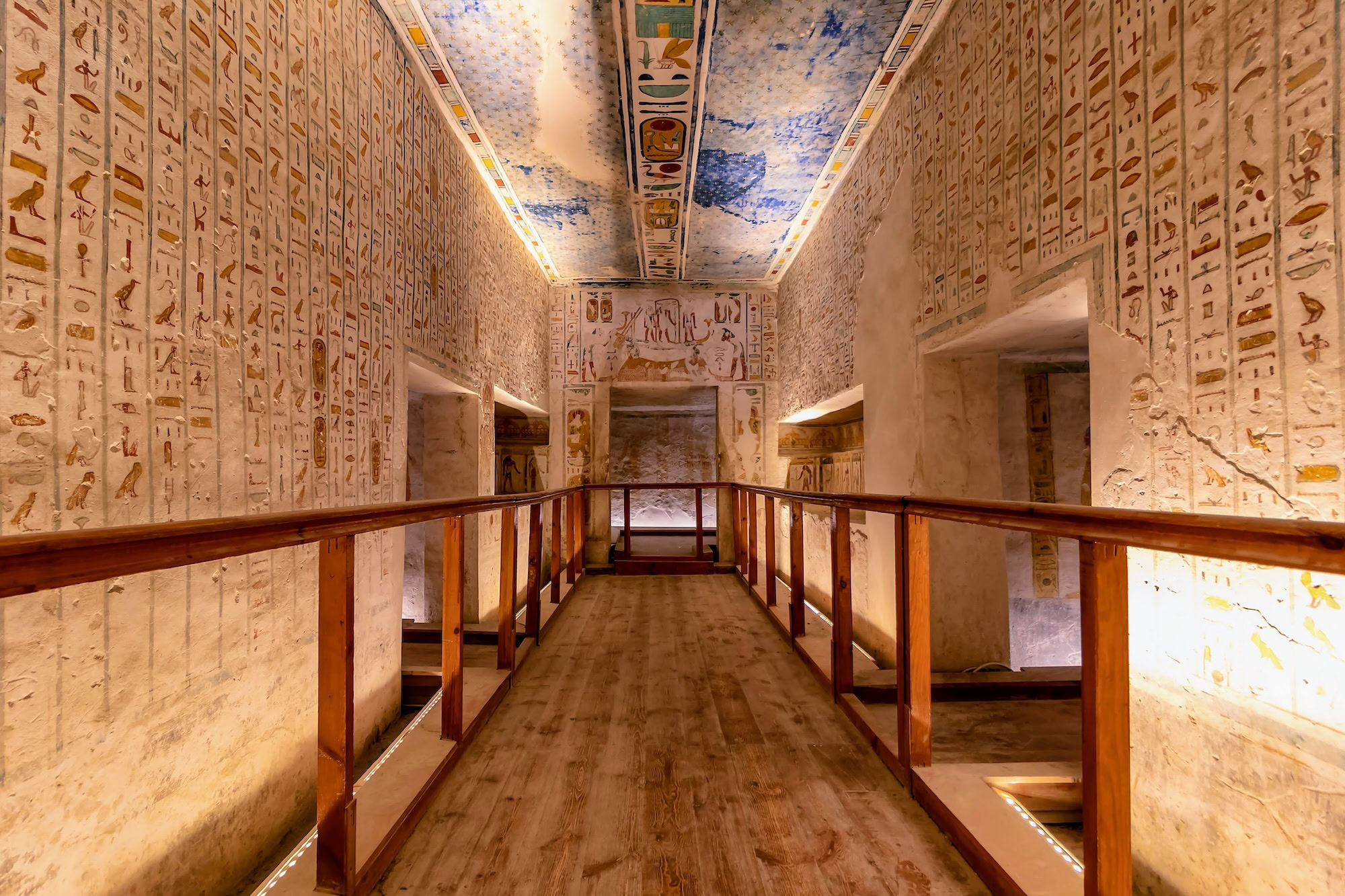 Interior of ancient Egyptian tomb in Valley of the Kings with hieroglyphic walls and modern walkways for guided tours