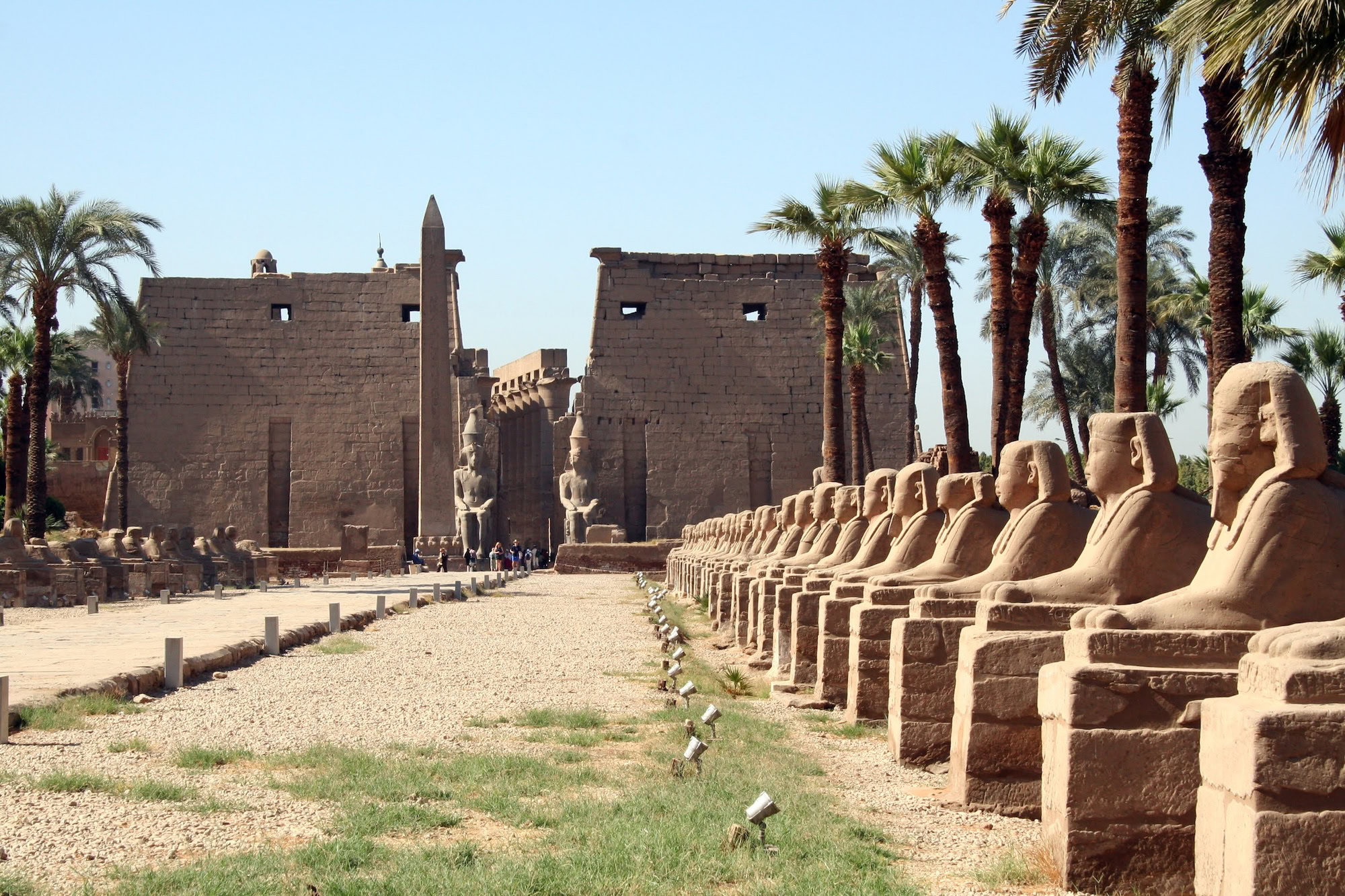 Ram-headed sphinx statues at Karnak Temple Complex with obelisk and ancient columns