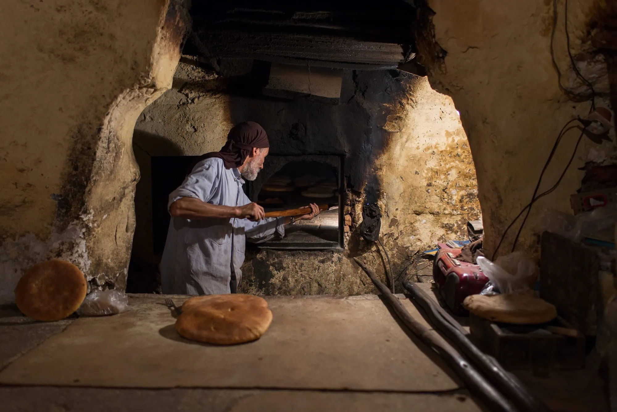 Traditional baker working at stone oven making fresh bread