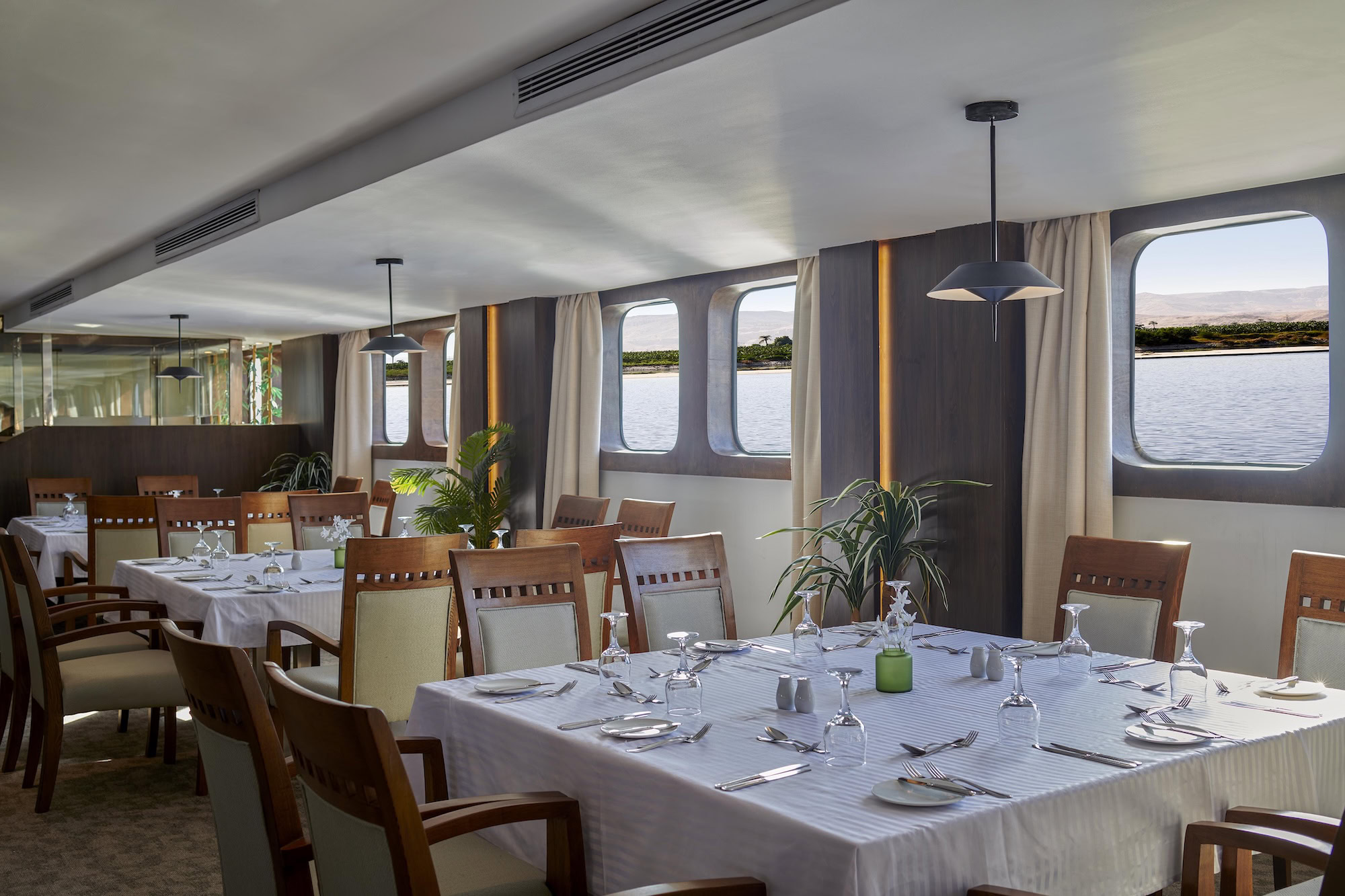 Elegant cruise ship restaurant dining room with tables and river view