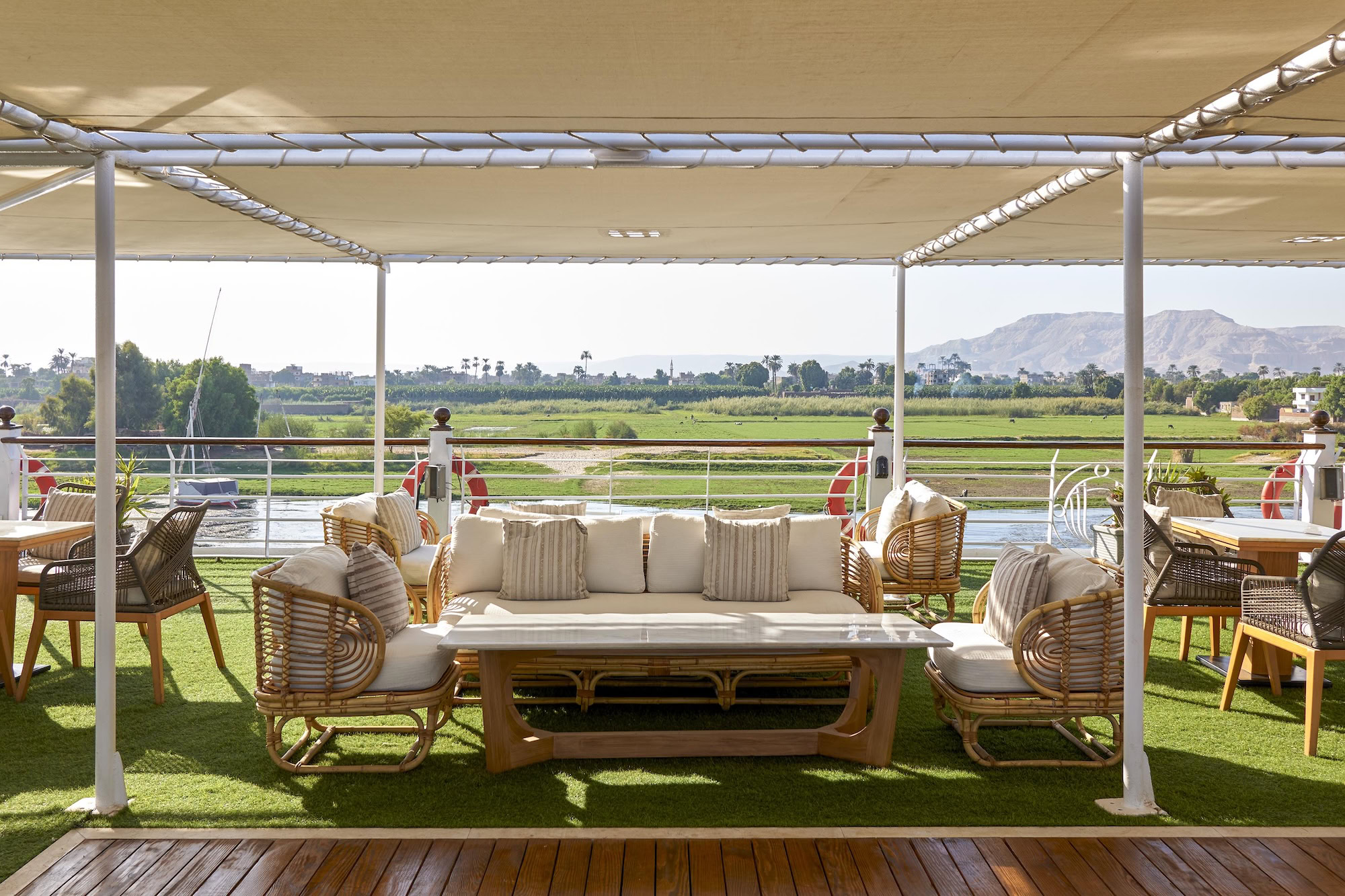 Barco de cruzeiro de luxo no rio Nilo com assentos confortáveis ao ar livre e vistas panorâmicas do rio