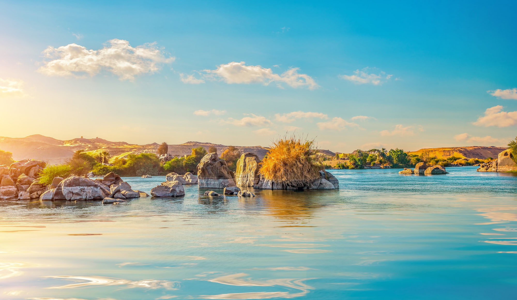 Vista majestuosa del río Nilo con rocas de granito, islas y palmeras en el paisaje desértico de Egipto