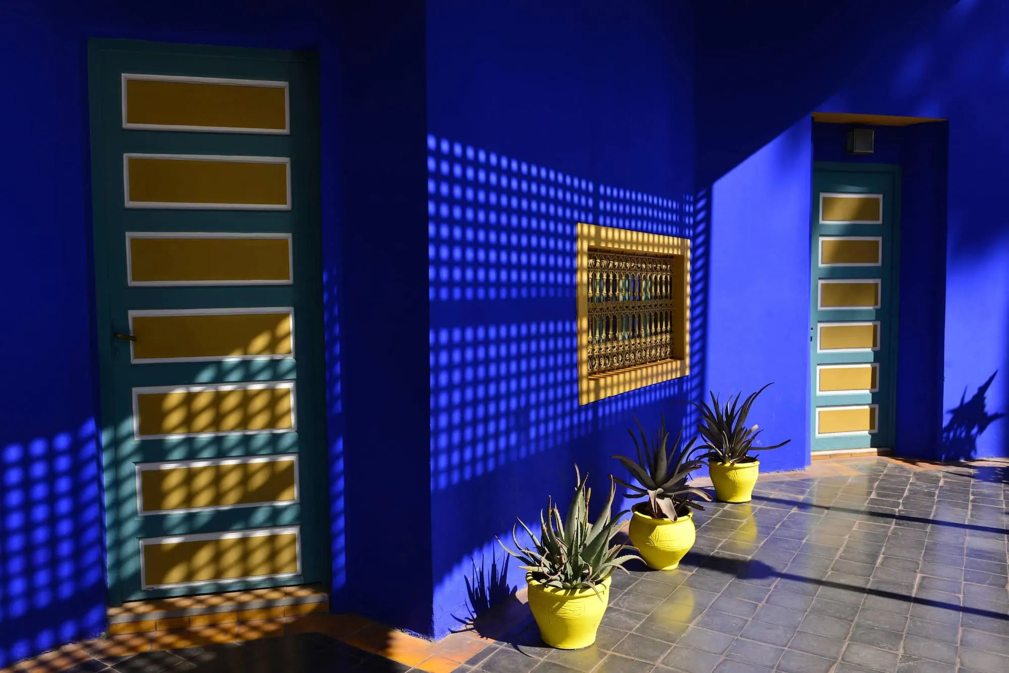 Majorelle Gardens featuring vibrant blue walls with teal decorative elements and yellow planters in Marrakech