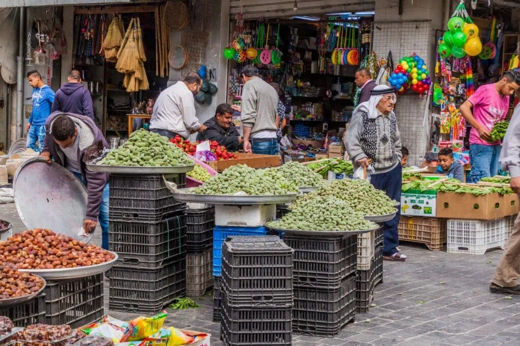 Market stalls displaying dates and fresh almonds in an outdoor market area, Irbid