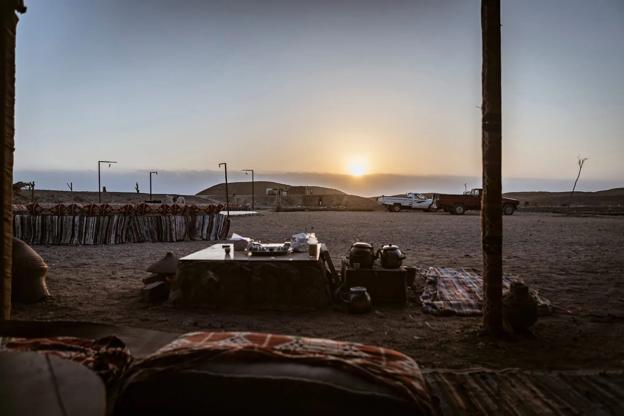 Desert camping setup with tent, truck and traditional camp equipment in arid landscape