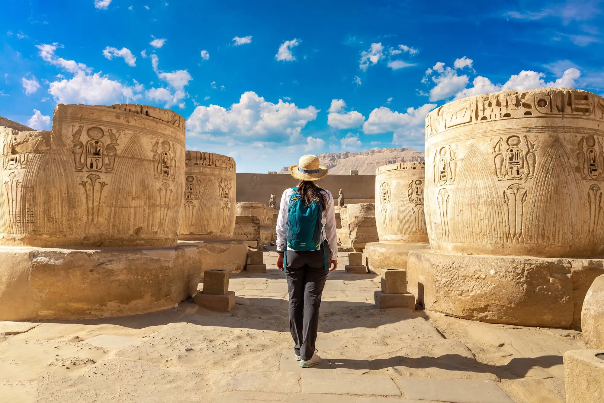 Turista com mochila explorando templo antigo egípcio com colunas e hieróglifos