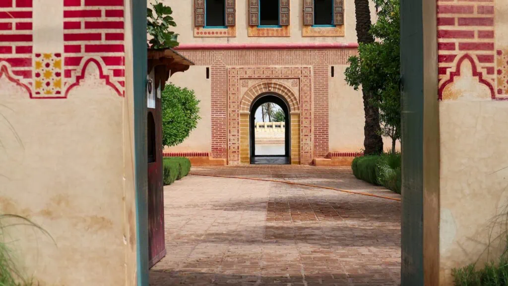 Menara Garden entrance with arched doorway, tiled pathway, and pavilion facade with olive trees, Marrakesh