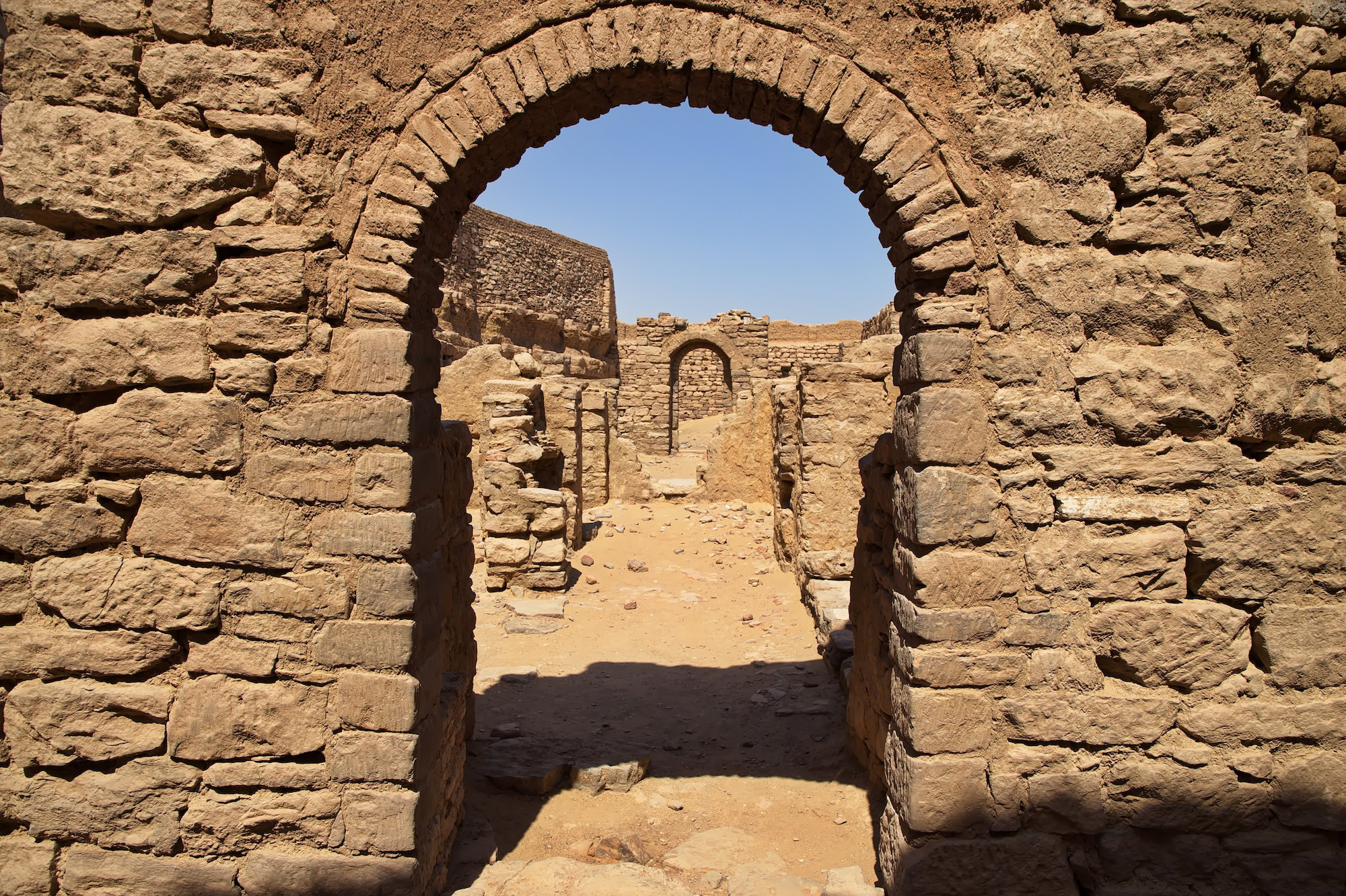 Ancient stone ruins of St. Simeon Monastery showing weathered sandstone archway and walls