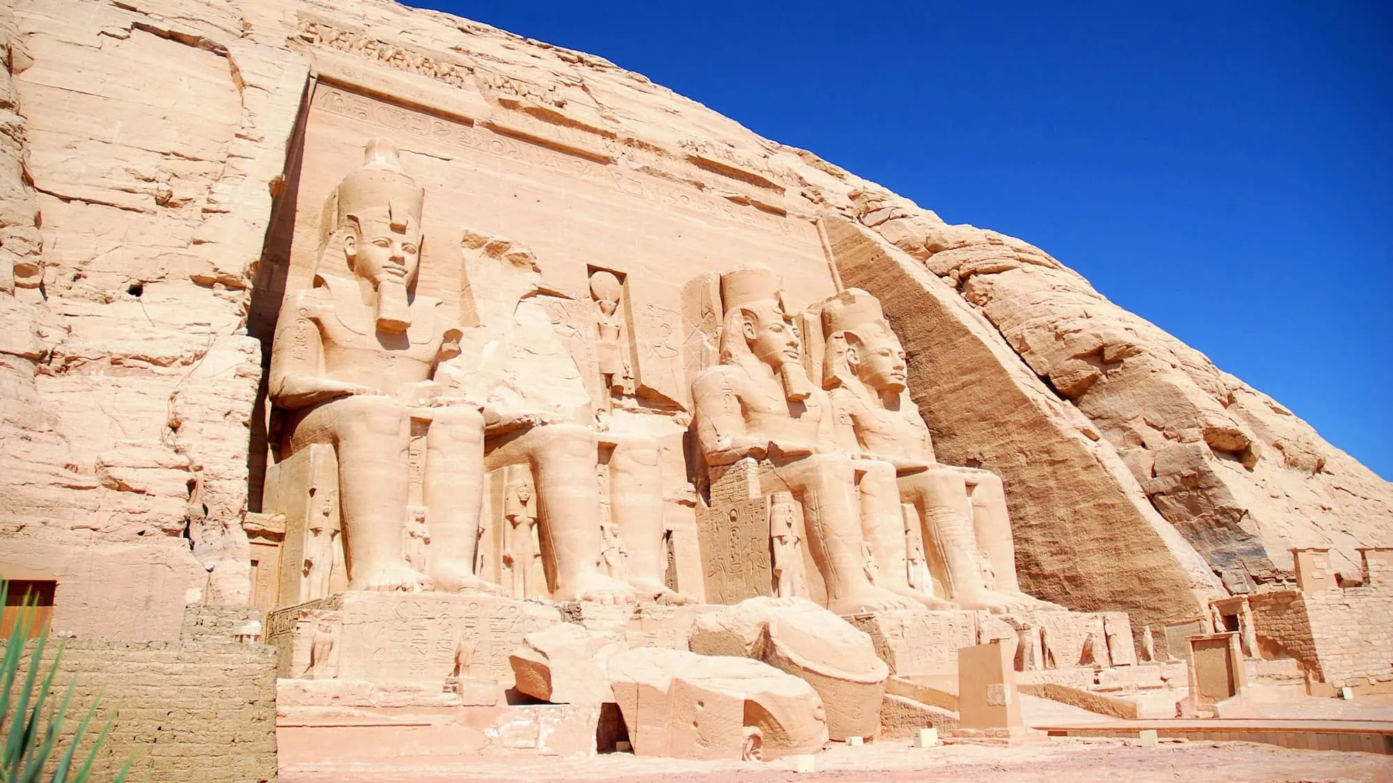 Massive colossal statues of pharaohs carved into rock face at Abu Simbel temples