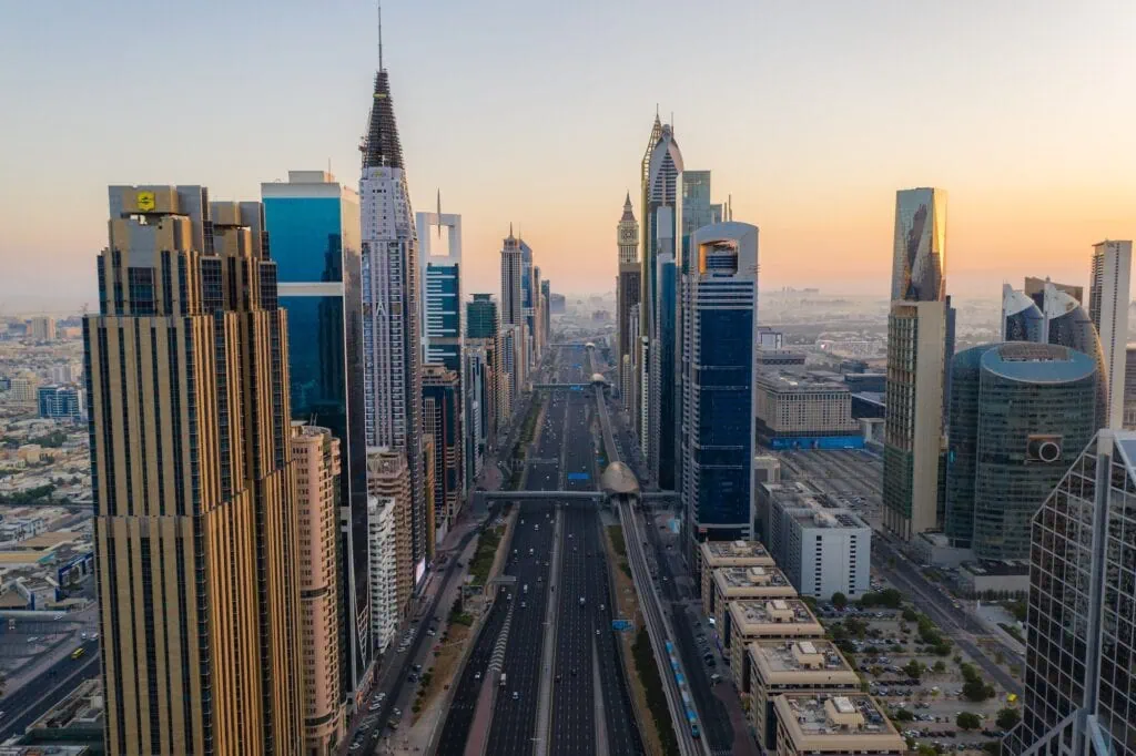 Morning rush hour traffic metro trains and modern skyscrapers on Sheikh Zayed Road during sunrise