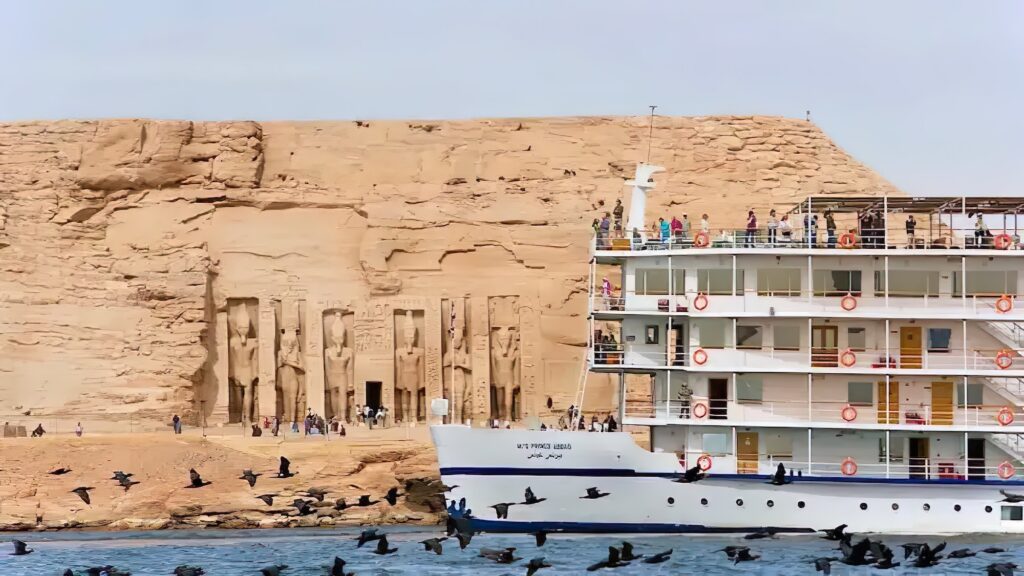 Elegant Nile cruise ship sailing past the colossal rock-cut statues of Abu Simbel Temple, Abu Simbel