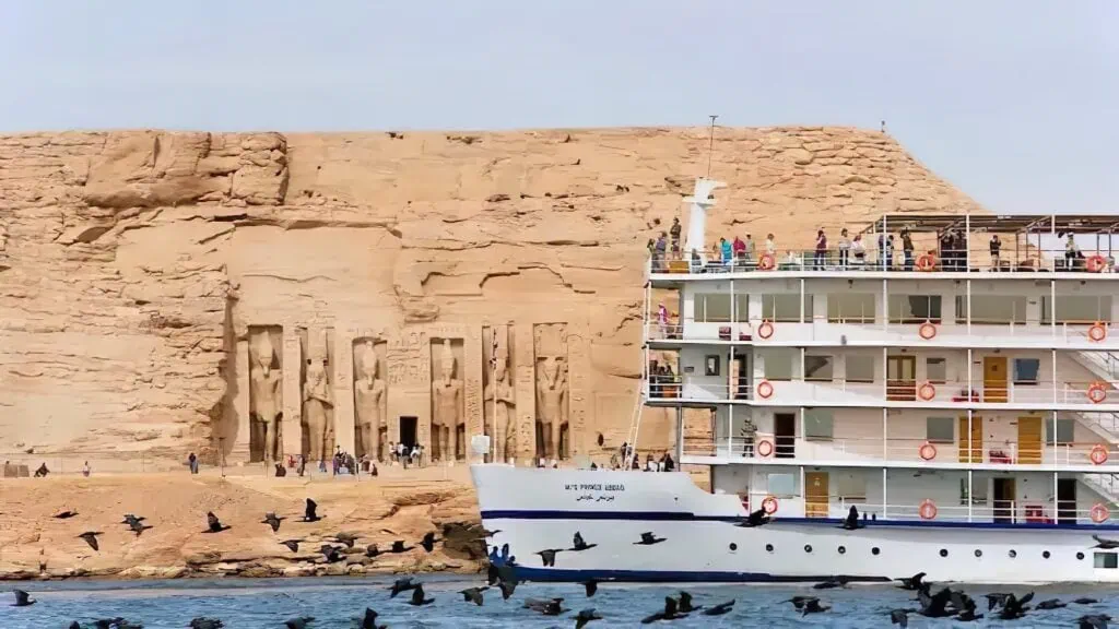 Elegant Nile cruise ship sailing past the colossal rock-cut statues of Abu Simbel Temple, Abu Simbel