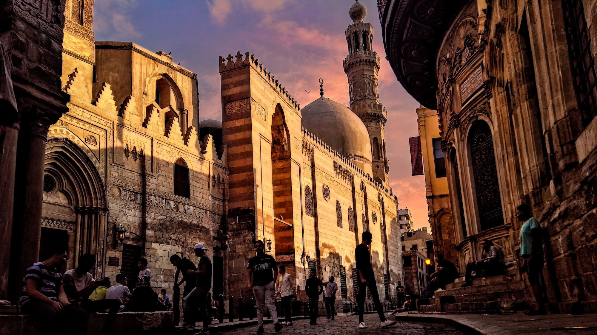 Tourists walking through crowded narrow street in Islamic Cairo historic district