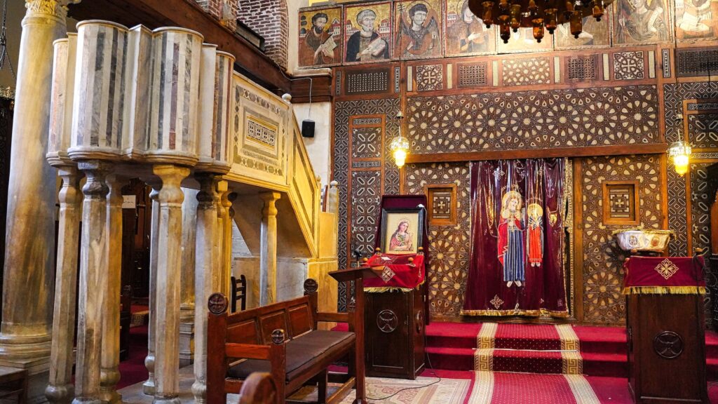 The nave with marble pulpit, columns, and carved wooden iconostasis inside the Coptic Orthodox Church of Saint Barbara, Cairo