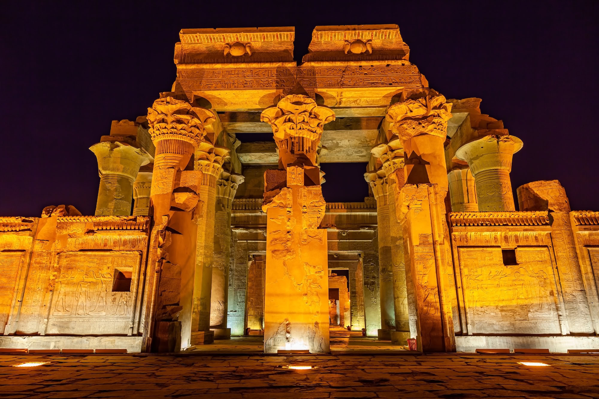 Ancient Egyptian temple columns with hieroglyphs illuminated at night at Kom Ombo Temple
