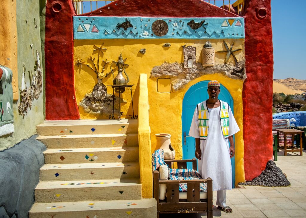 Local man standing beside a colorful house in the Nubian Village, Aswan