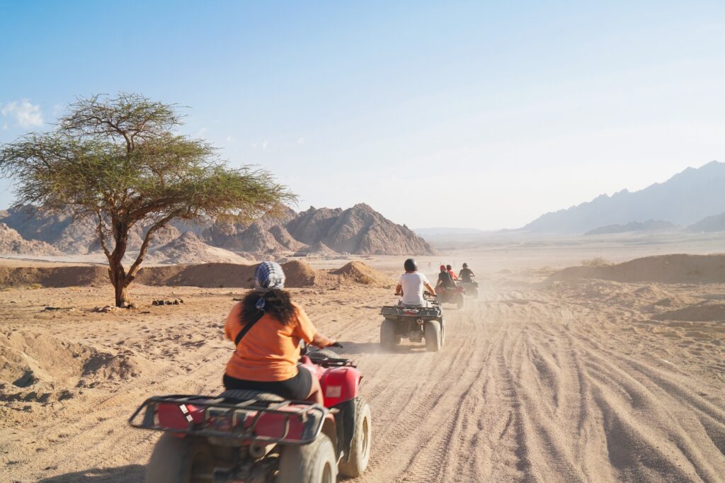 People driving quad bikes across a wide desert landscape