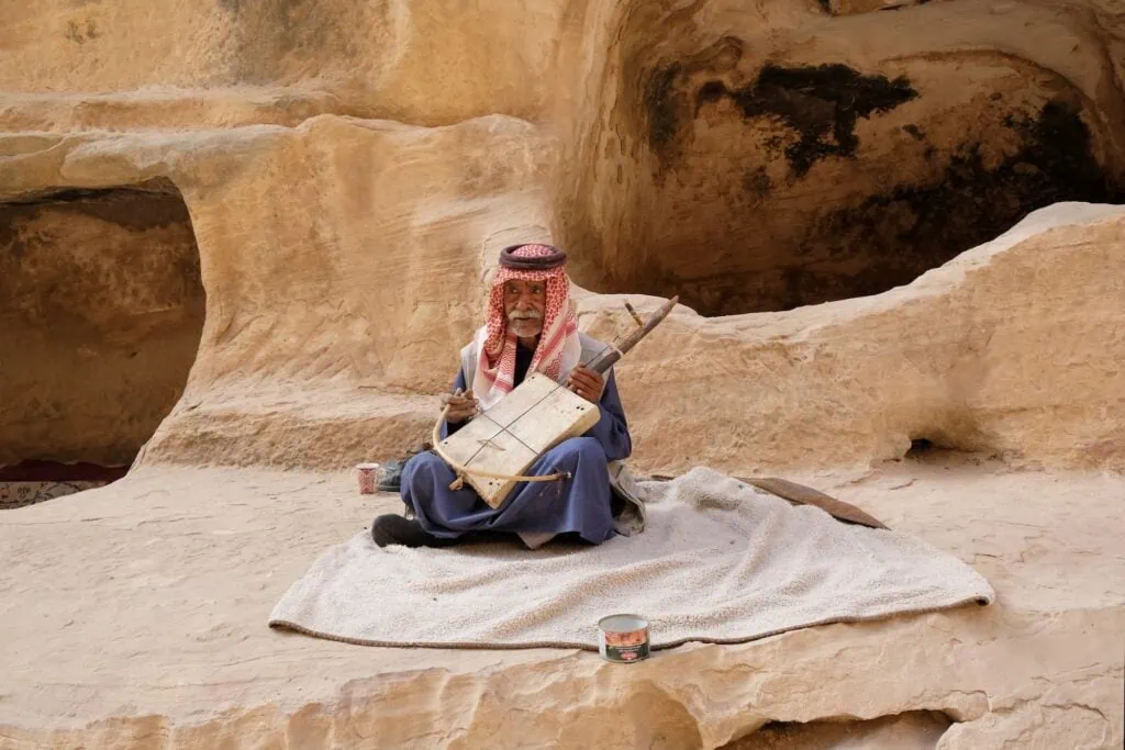 Old Jordanian man in traditional dress holding an Arab rebab string instrument in Little Petra, Wadi Musa