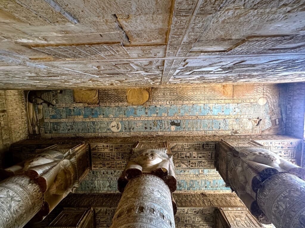Painted ceiling with astronomical motifs and Hathor faces above carved columns inside Dendera Temple, Dendera