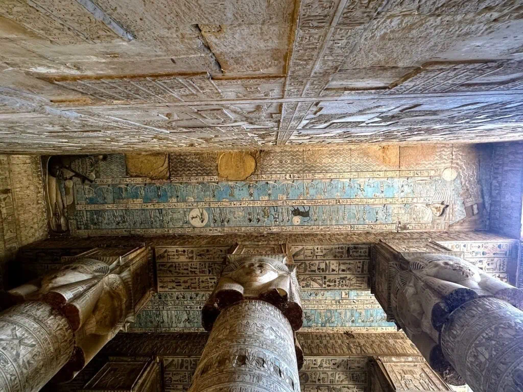 Painted ceiling with astronomical motifs and Hathor faces above carved columns inside Dendera Temple, Dendera