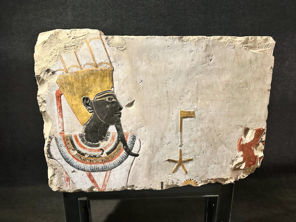 Painted limestone relief fragment depicting a crowned figure displayed inside the Luxor Museum, Luxor