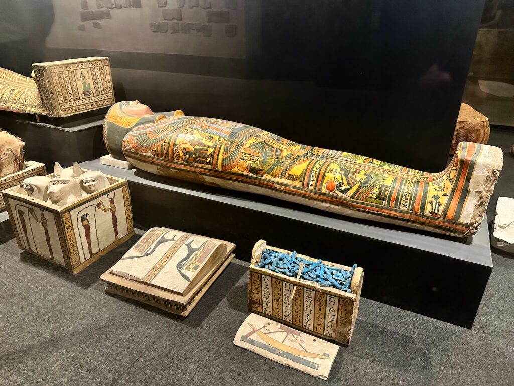 Painted wooden sarcophagus with funerary objects displayed inside the Luxor Museum, Luxor