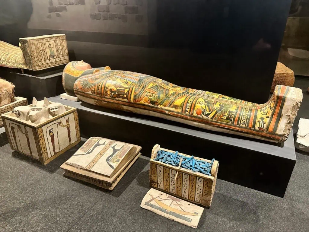 Painted wooden sarcophagus with funerary objects displayed inside the Luxor Museum, Luxor