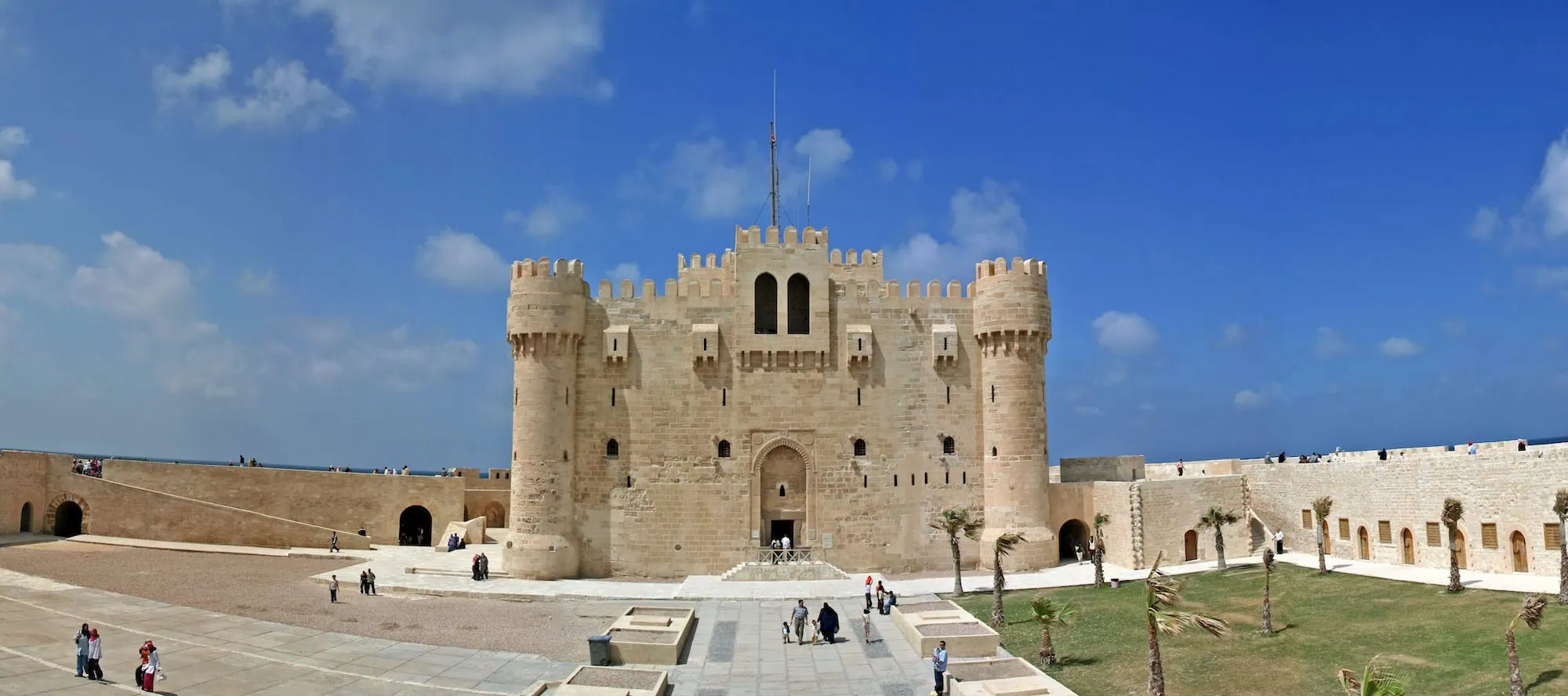Qaitbay Citadel fortress with stone walls, towers, and tourists in Alexandria