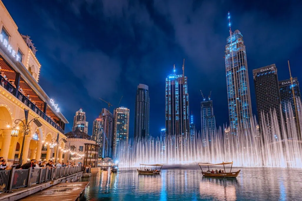 The Dubai Fountain water show on Burj Khalifa Lake at night, with the Burj Khalifa and downtown Dubai high-rises in the background — synchronised fountain choreography performed every 30 minutes after sunset