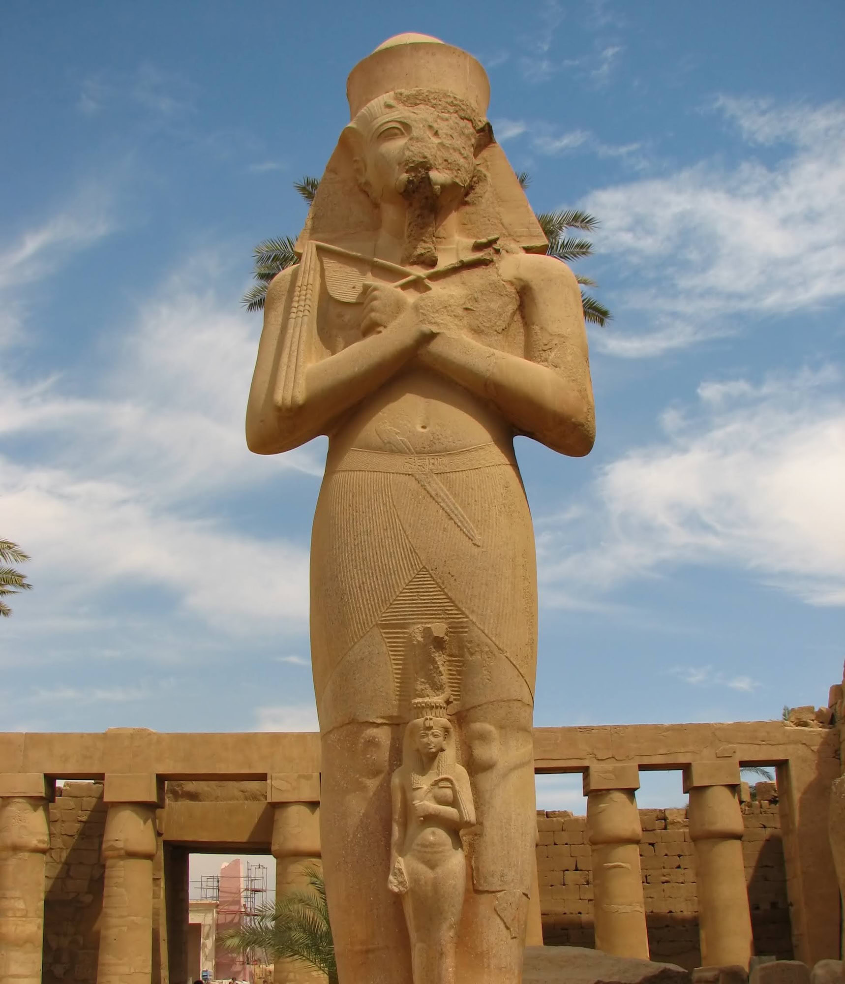 Pharaoh statue among massive hieroglyphic columns inside Karnak Temple