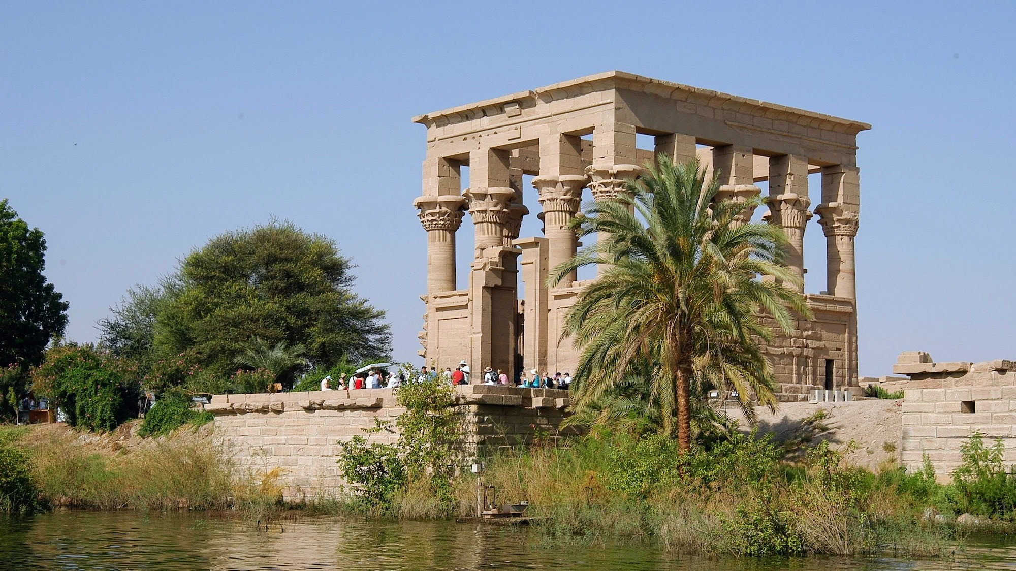 Ancient Philae Temple columns and stone carvings with tourists exploring the ruins