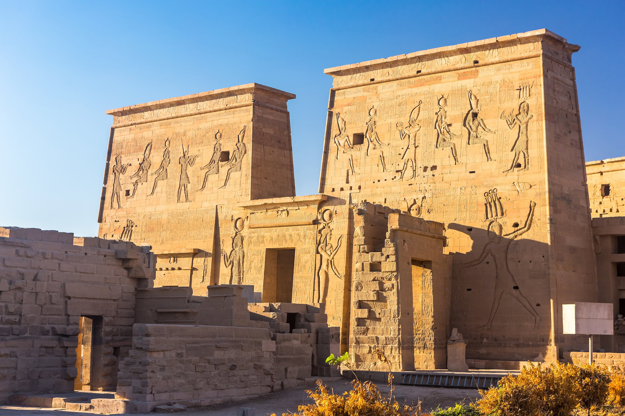 Ancient Egyptian temple pylons at Philae with hieroglyphic reliefs depicting gods and pharaohs