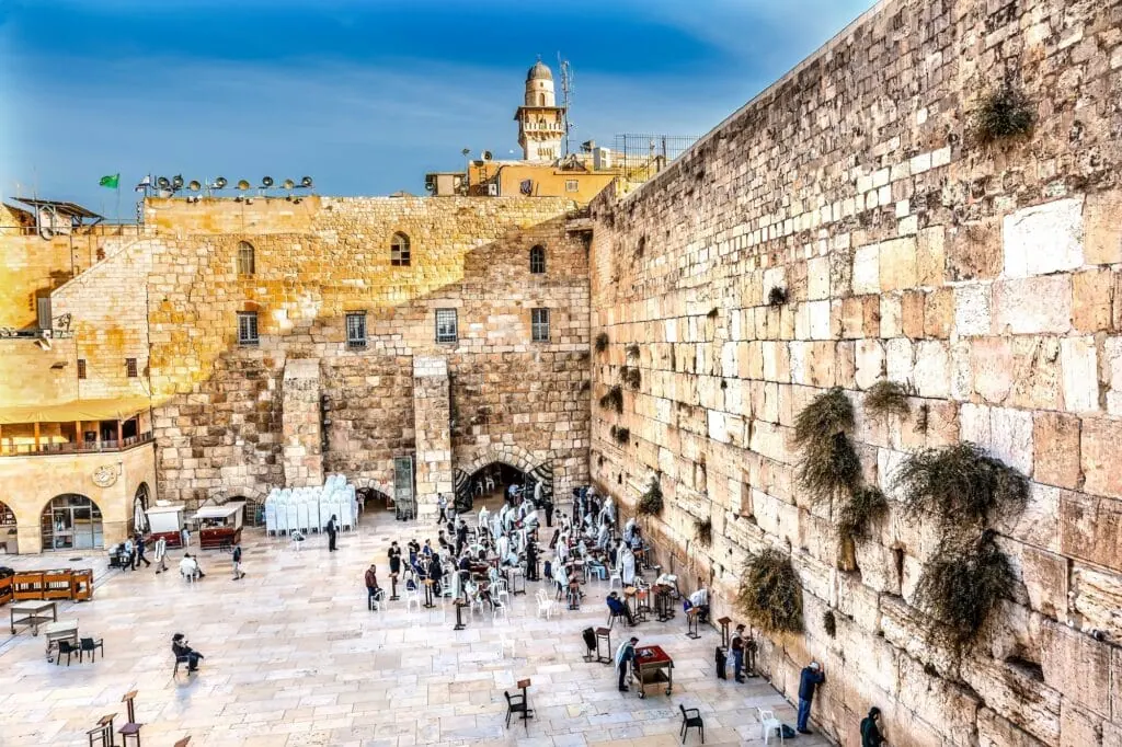 People praying at the Western Wall of the Temple Mount complex with stone blocks and prayer area visible, Jerusalem