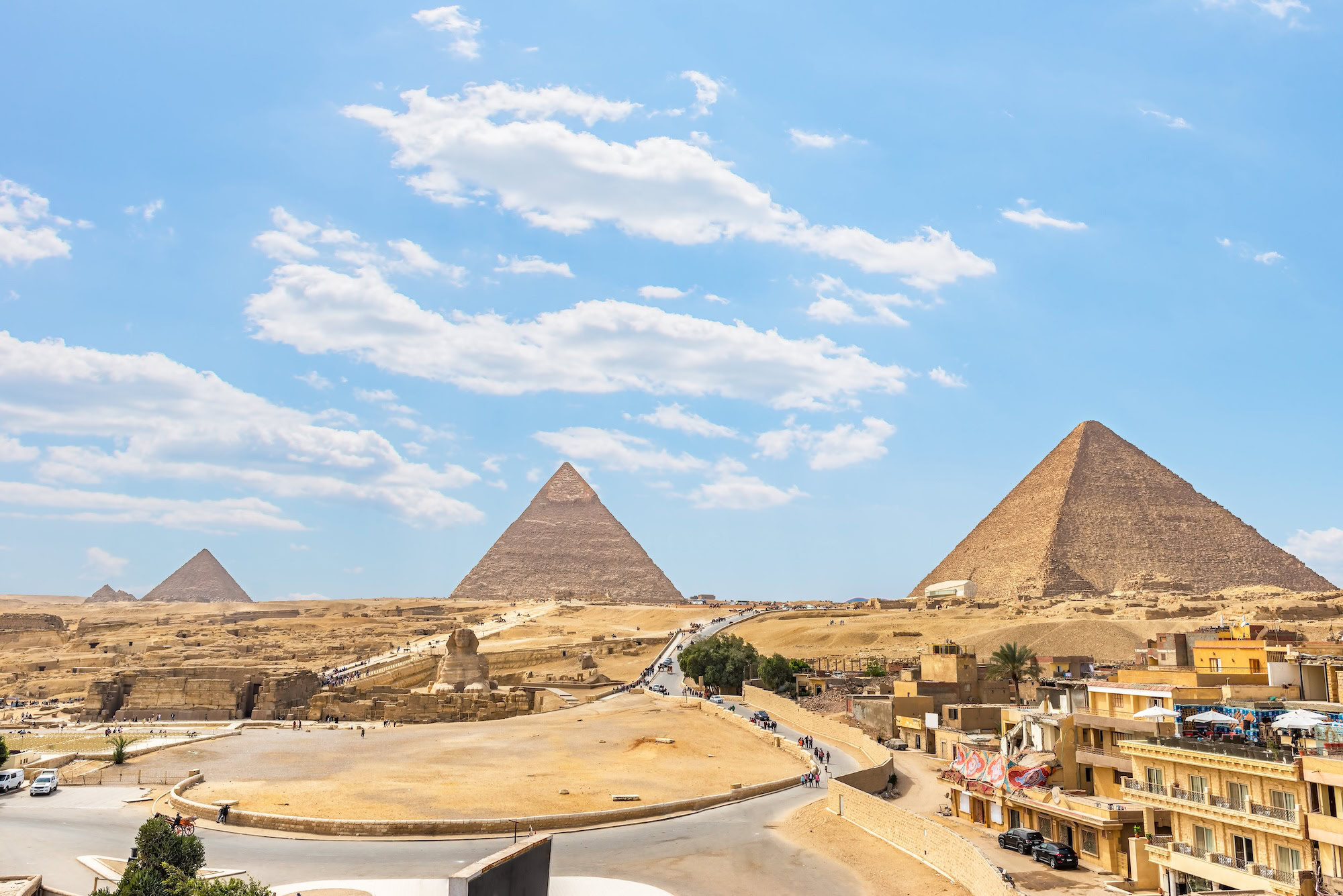 Great Pyramids of Giza and Sphinx with moderate tourist crowds on desert landscape