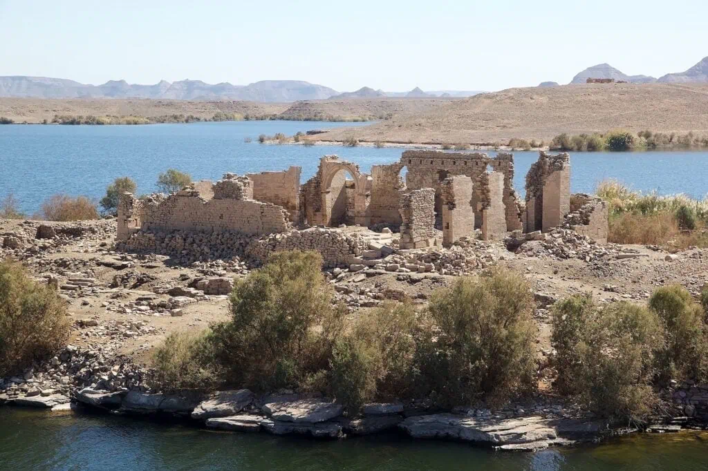 The ruins of the Kasr Ibrim fortress on a small rocky island in Lake Nasser, surrounded by the blue water of the reservoir in Lower Nubia.